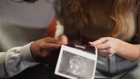 Junges-Paar-Hält-Ultraschallbilder-Des-Babys-Im-Zimmer