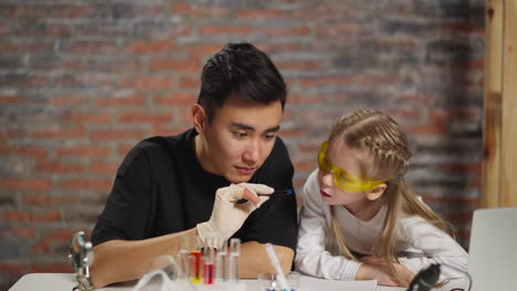 Asian-scientist-and-little-student-look-at-crystal-in-lab