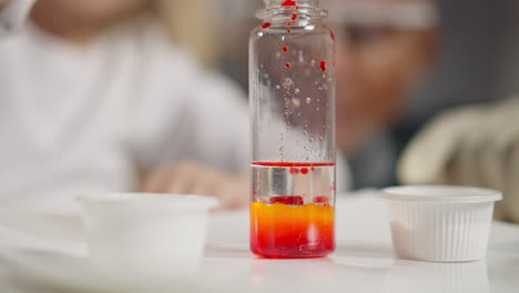 Girl-drips-paint-into-clear-liquid-performing-chemical-test