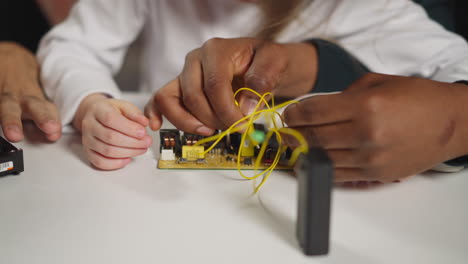 Technician-teaches-girl-to-connect-wires-with-probes-to-chip