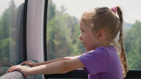 Amazed-little-child-girl-looks-at-mountains-from-cable-way
