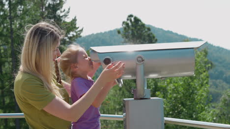 Blonde-woman-with-daughter-adjusts-tower-viewer-on-ground