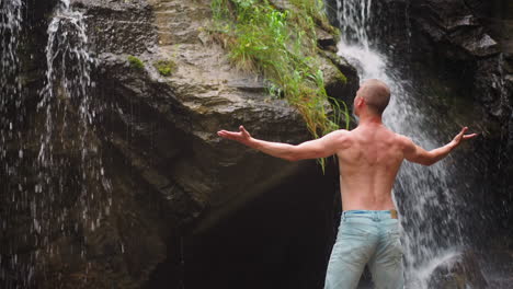 Shirtless-man-happy-of-bonding-with-nature-near-waterfall
