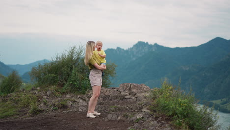 Woman-prohibits-son-to-suck-fingers-standing-on-rocky-hill