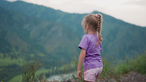 Little-girl-looks-at-old-distant-mountains-and-scratches-leg