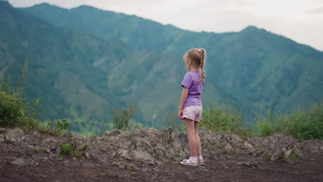 Thoughtful-little-girl-looks-at-old-mountain-silhouettes