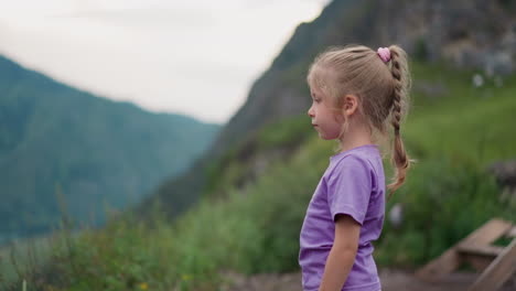 Calm-litle-child-stands-on-hill-looking-at-distant-mountains
