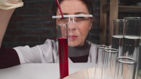 Asian-woman-with-goggles-drips-catalyzer-into-test-tube