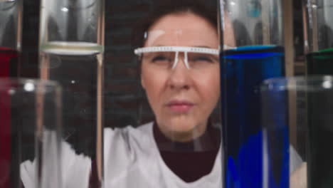 Squinting-female-researcher-drips-catalyzer-into-test-tube