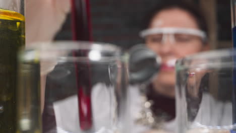 Woman-with-magnifier-glass-shakes-test-tube-with-red-liquid