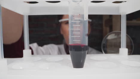 Doctor-turns-plastic-test-tube-with-scale-and-blood-sample