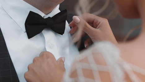 Lady-bride-adjusts-bow-tie-on-neck-of-young-groom-at-wedding