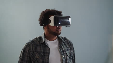 Black-guy-with-VR-helmet-turns-around-on-grey-background