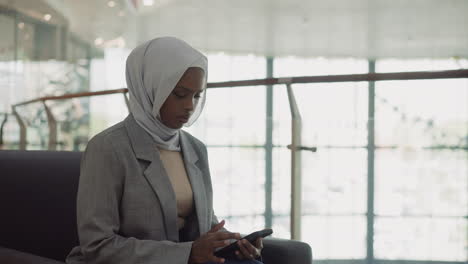 African-American-business-woman-in-hijab-texts-on-phone