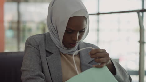 Schwarze-Dame-Mit-Hijab-Schaut-In-Die-Einkaufstasche-Im-Einkaufszentrum