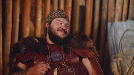 Positive-man-on-tribal-costume-with-fur-smiles-in-cabin