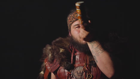 Obese-man-in-ethnic-leather-costume-smokes-shaman-pipe