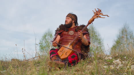 Dreaming-man-plays-stringed-instrument-sitting-on-hill-grass