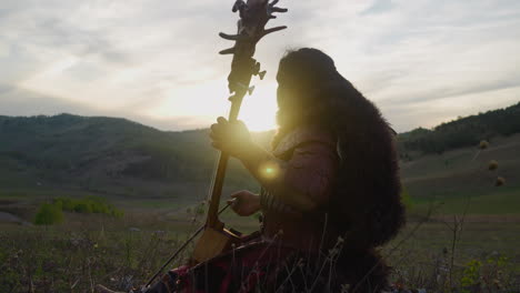 Folk-musician-plays-tovshuur-with-bow-in-mountain-valley