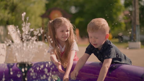 Little-boy-and-elder-girl-play-with-water-in-inflatable-pool