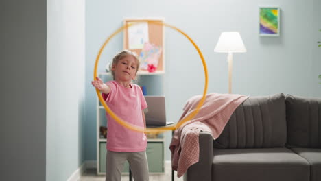 child-diligently-hula-hooping-in-bright-room-where-there-is-notebook