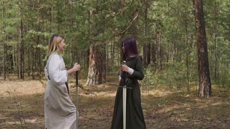 Girls-in-long-vintage-medieval-dresses-hold-swords-in-forest