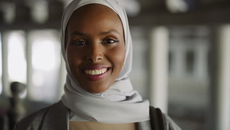 Joyful-black-lady-with-hijab-smiles-to-camera-on-city-street