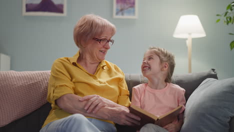 Oma-Und-Mädchen-Lachen-über-Einen-Lustigen-Moment-Im-Buch-Zu-Hause