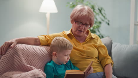 Little-grandson-tries-to-read-book-to-loving-grandma-at-home