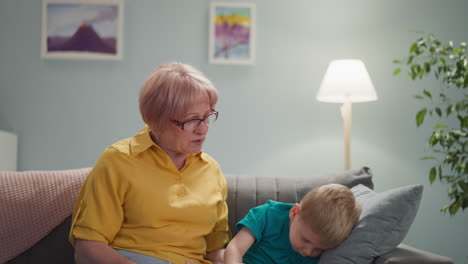 Granny-tries-to-calm-down-naughty-grandson-playing-on-sofa