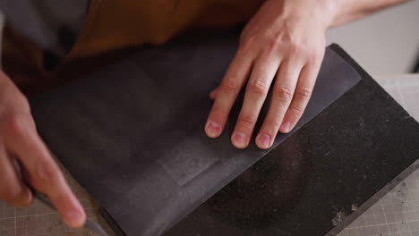 Worker-sharpens-cutter-with-sandpaper-at-table-in-workshop