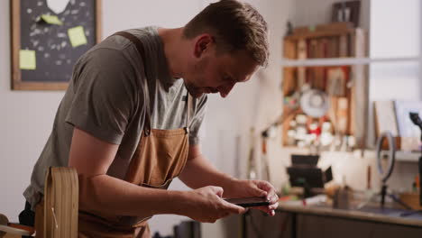 Worker-in-apron-takes-photo-of-handmade-wallet-in-studio