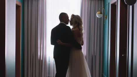 Cute-couple-silhouettes-of-bride-and-groom-hug-by-window