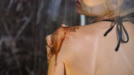 Woman-puts-coffee-scrub-on-shoulder-showering-at-home