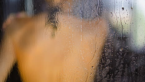 Water-drops-run-down-glass-cabin-wall-woman-enjoys-shower