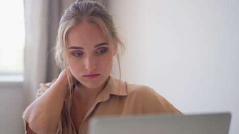Young-blonde-woman-feels-tired-sitting-in-office-with-laptop