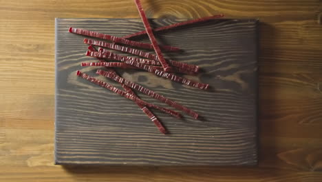 Man-hands-drop-jerked-red-fish-sticks-onto-wooden-board