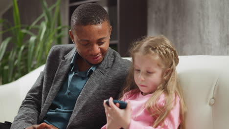 African-American-carer-man-with-girl-watches-family-videos