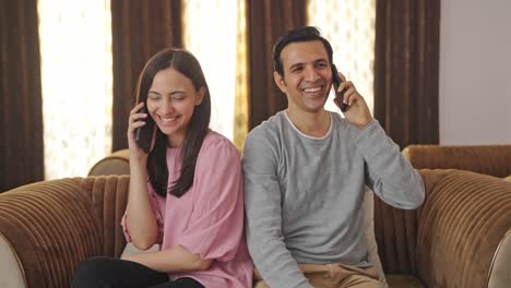 Glückliches-Indisches-Paar,-Das-Mit-Seinen-Mobiltelefonen-Spricht