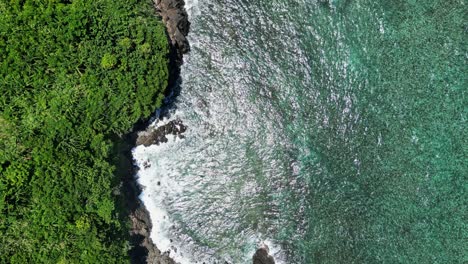 Drone-bird's-eye-view-above-stunning-lush-tropical-shorelines-and-green-ocean-water