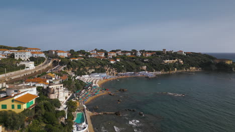 Italy-Tuscan-beach-coastline-homes-as-waves-roll-into-bay,-drone