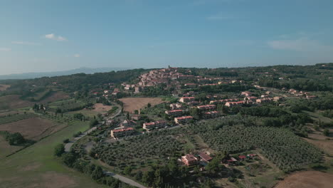 Tuscan-settlement-on-the-top-of-the-hill,-distant-aerial-view,-italy