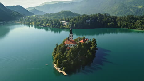 Drohnen-Umlaufbahn-Um-Die-Slowenische-Insel-Bled,-Flacher-See,-Lange-Schatten