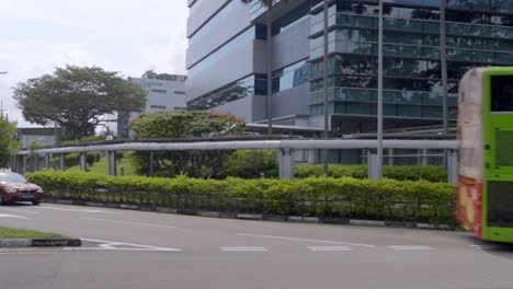 Grüner-öffentlicher-Doppeldeckerbus,-Gefolgt-Von-Einem-Auto,-Das-An-Der-Kreuzung-Im-Changi-Business-Park-In-Singapur-Links-Abbiegt