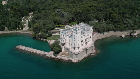 Drone-pulls-back-and-tilts-up-to-reveal-Italy-Trieste,-Miramare-Castle