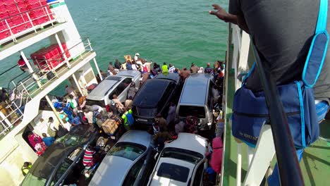 Tilt-down-bird's-eye-view-of-people-and-vehicles-inside-Kunta-Kinteh-ferry-sailing-from-Banjul-to-Barra---Gambia,-West-Africa