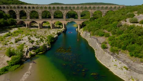 Aerial-establishing-shot-of-the-Pont-Du-Gard-with-locals-swimming-and-playing-in-the-river