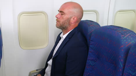 A-nervous-man-with-a-beard-taking-deep-breaths-trying-not-to-panic-with-anxiety-on-a-passenger-plane-airliner-airplane