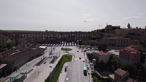 Aerial-view-circling-across-the-Aqueduct-of-Segovia,-Avenue-Via-Roma-and-Padre-Claret-Spanish-old-town-skyline