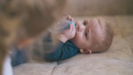 Kleines-Baby-Trinkt-Wasser-Aus-Der-Flasche-Und-ältere-Schwester-Auf-Dem-Bett